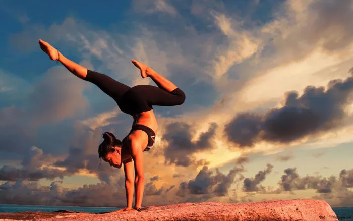 Người phụ nữ mặc đồ thể thao tập yoga trên đá bên bờ biển và cảnh mây 4K  tải xuống hình nền