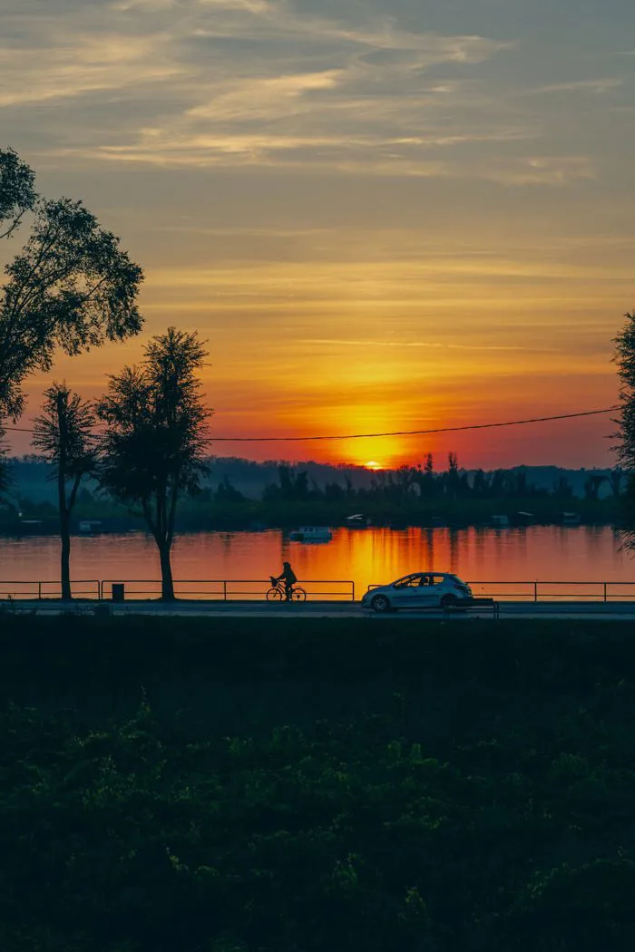 Hình ảnh miễn phí: Hình ảnh người đạp xe trên con đường cạnh hồ nước lúc hoàng  hôn với ánh nắng vàng cam rực rỡ trên bầu trời